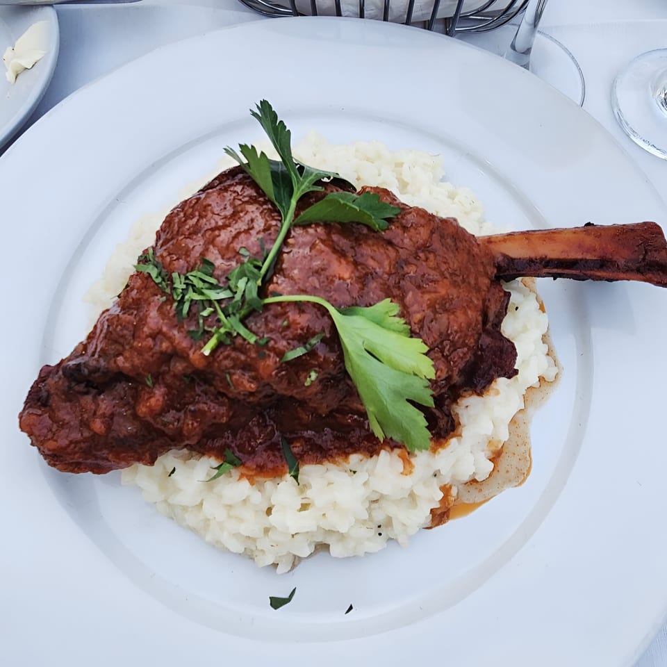 Braised lamb shank with rich red sauce and fresh parsley, served over creamy risotto at Buona Sera Ristorante.