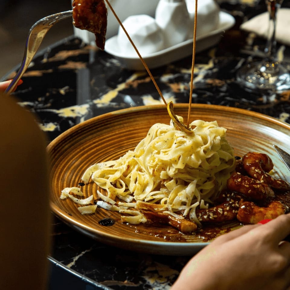 A close-up of a person eating Italian pasta with chicken and sauce at Buona Sera Ristorante.
