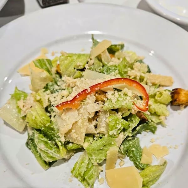 Buona Sera Ristorante's Caesar salad with romaine, parmesan, croutons, and red pepper on a white plate.