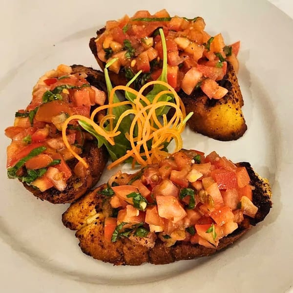 Three pieces of Buona Sera Ristorante's bruschetta, topped with diced tomatoes, basil, and carrot curls.