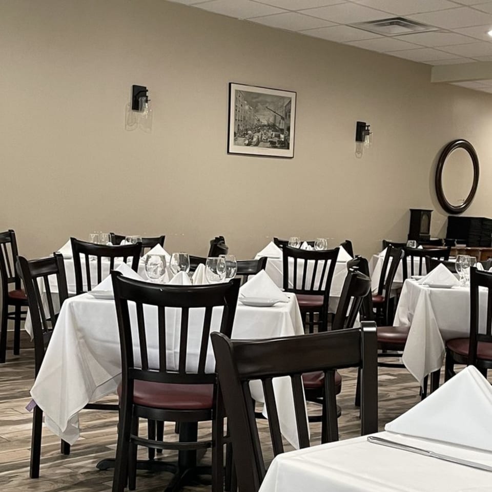 Dining room at Buona Sera Ristorante with set tables, dark wood chairs, and light walls.