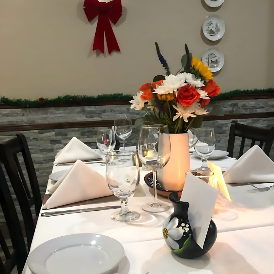 A set table at Buona Sera Ristorante with white tablecloths, wine glasses, and a floral centerpiece.